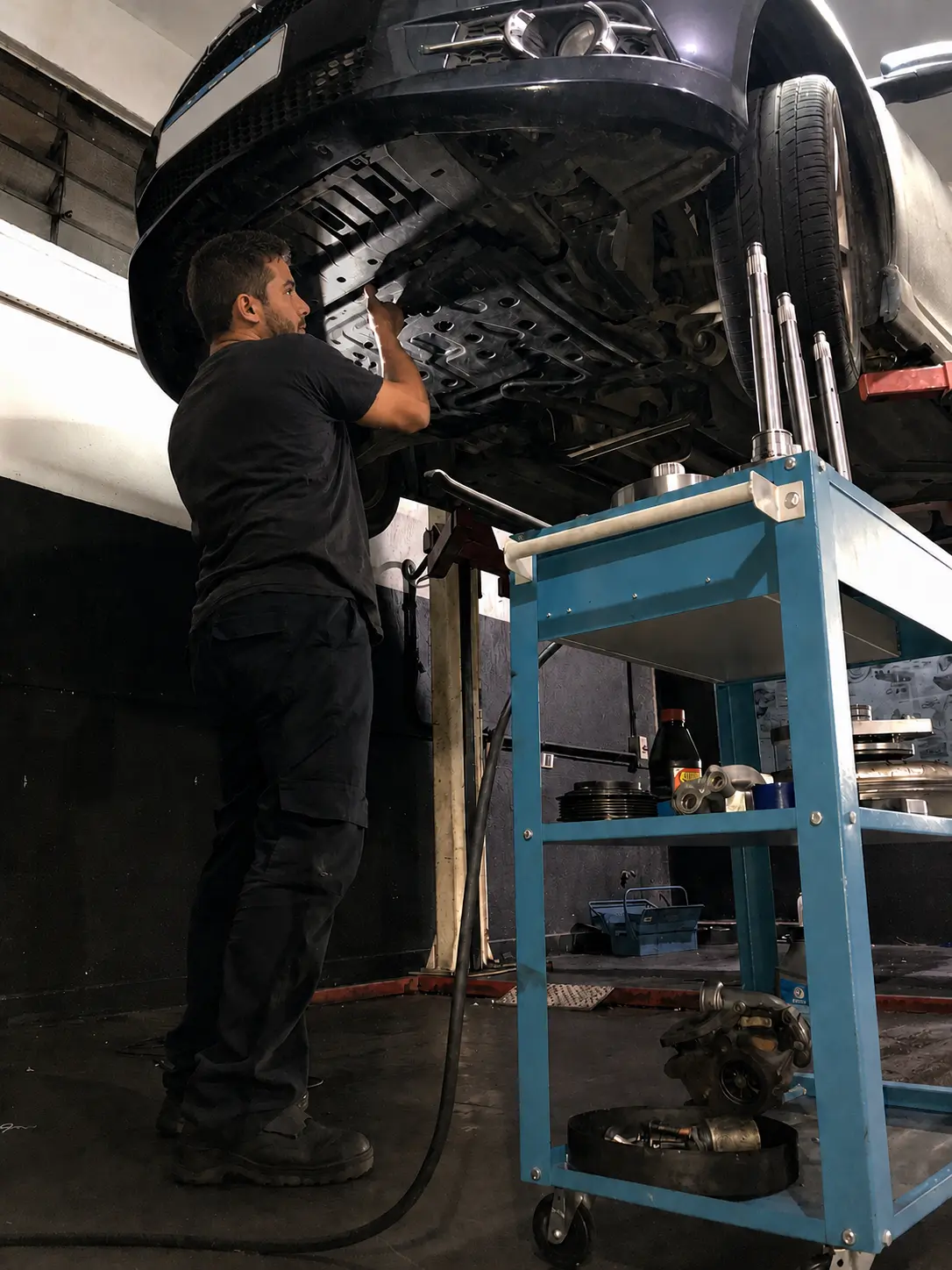 Técnico inspecionando a parte inferior de um carro no elevador